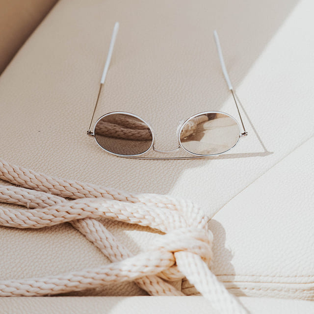 Neutral knitwear and sunglasses arranged on a table